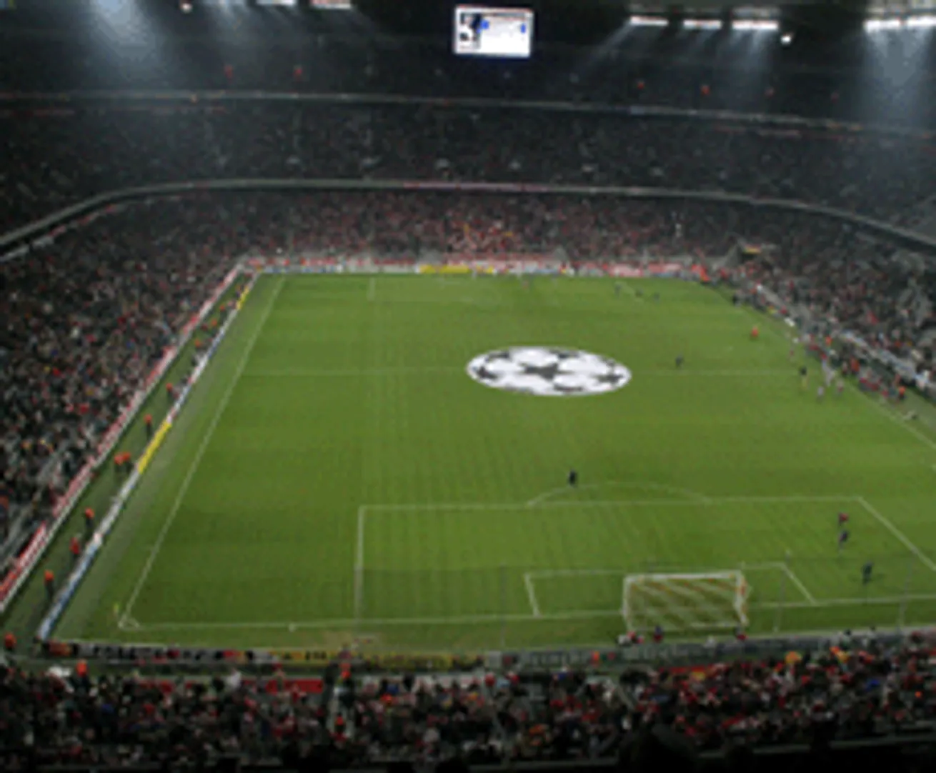 Ein Fußballstadion mit einer großen Anzeigetafel und einem Logo in der Mitte des Spielfeldes.