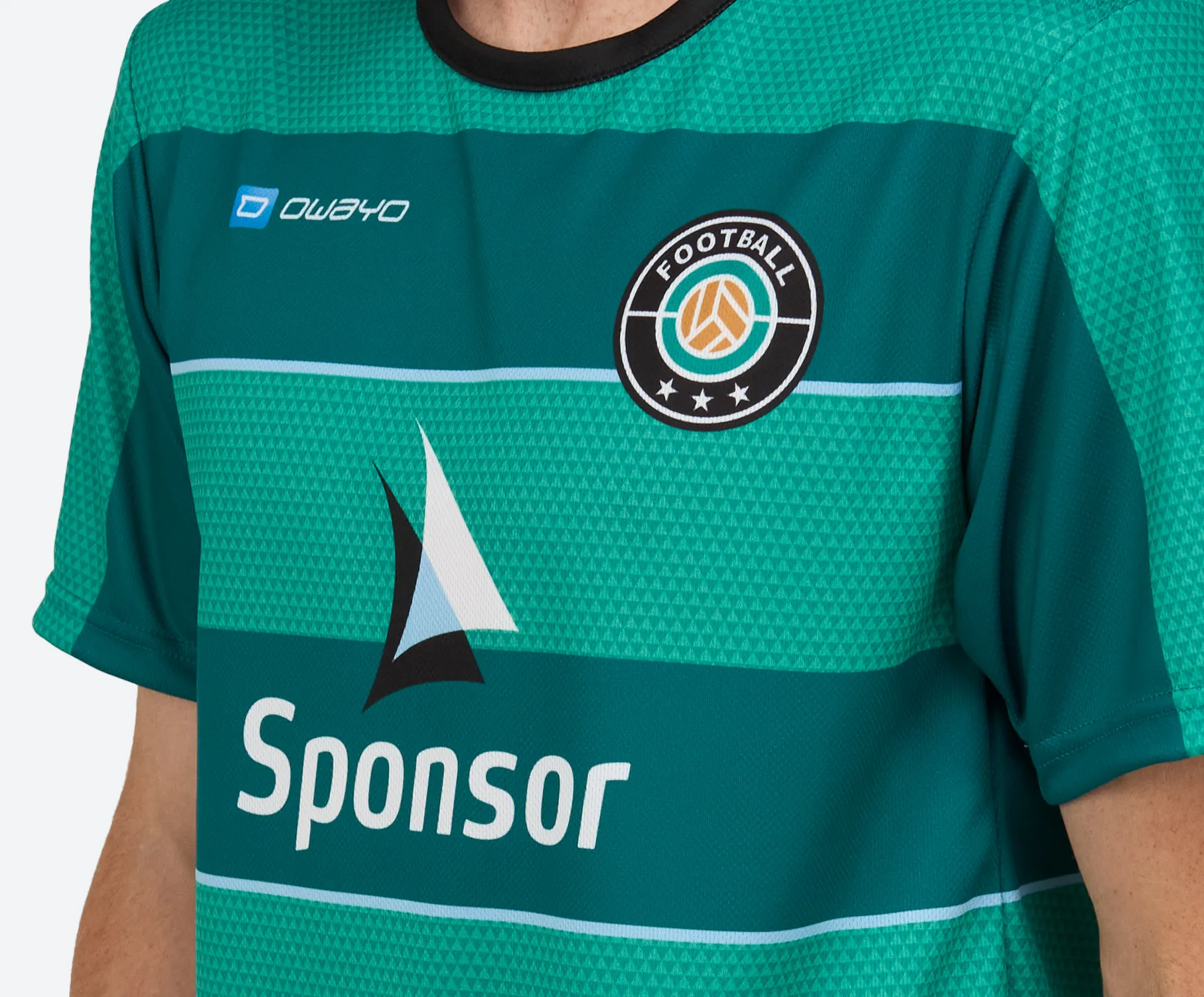 Ein grünes Fußballtrikot mit einem runden Emblem und Sponsorenlogo auf der Vorderseite.
