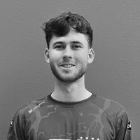 Ein Mann mit lockigem Haar und Bart trägt ein sportliches, gemustertes Oberteil mit dem Logo von owayo.